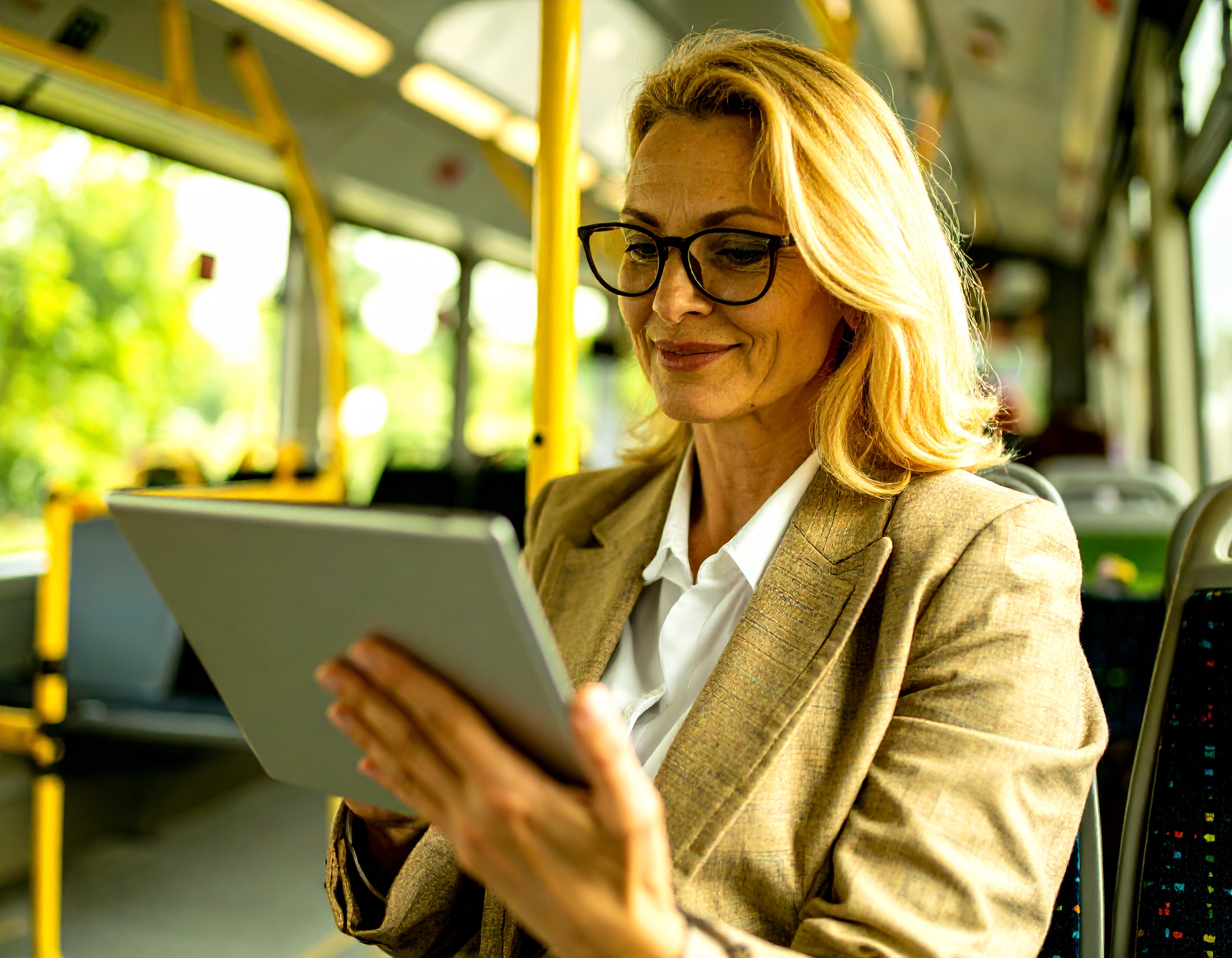Firefly Eine businessgekleidete Person (ca. 40 Jahre alt, stilvoll, modern) sitzt mit einem Tablet i Frau liest DIE RHEINPFALZ auf einem Tablet während einer Bus- oder Bahnreise.