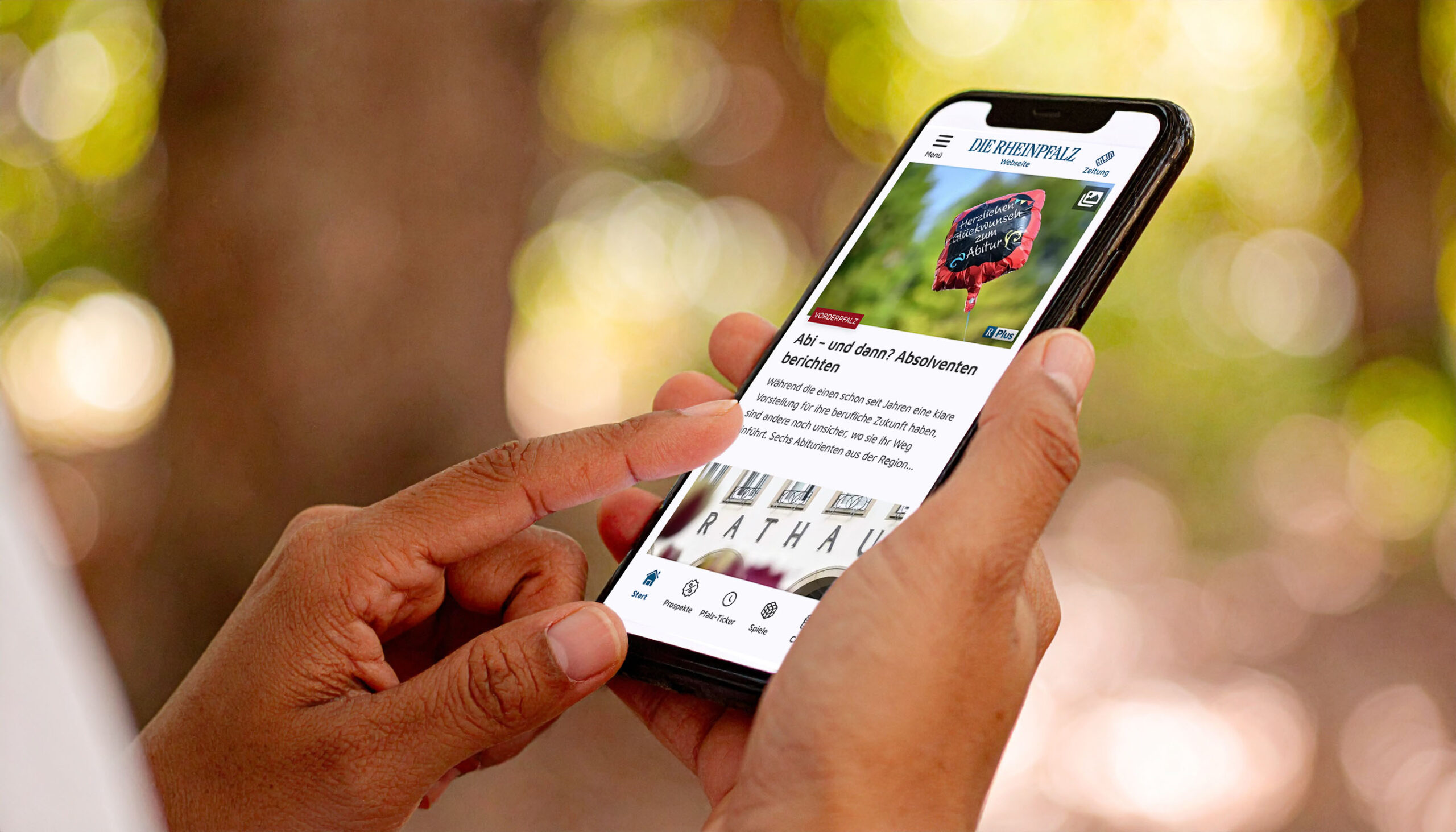 Hand Handy Wald App Person hält Smartphone mit der RHEINPFALZ-App – aktuelle Artikelübersicht geöffnet.