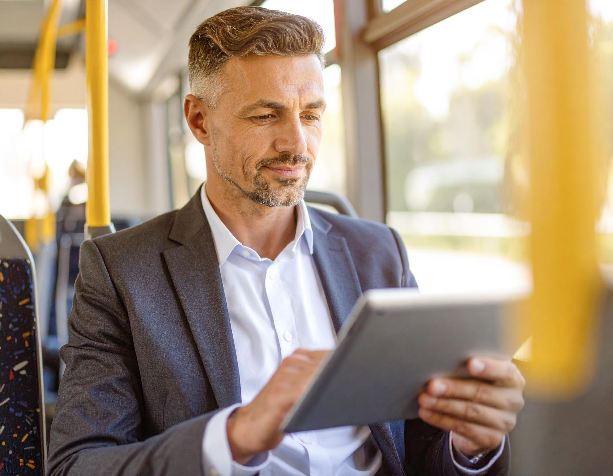 Mann Tablet ÖPNV 1 Klein Mann liest auf einem Tablet im Zug – steht für flexiblen digitalen Zugang zur RHEINPFALZ-Zeitung unterwegs