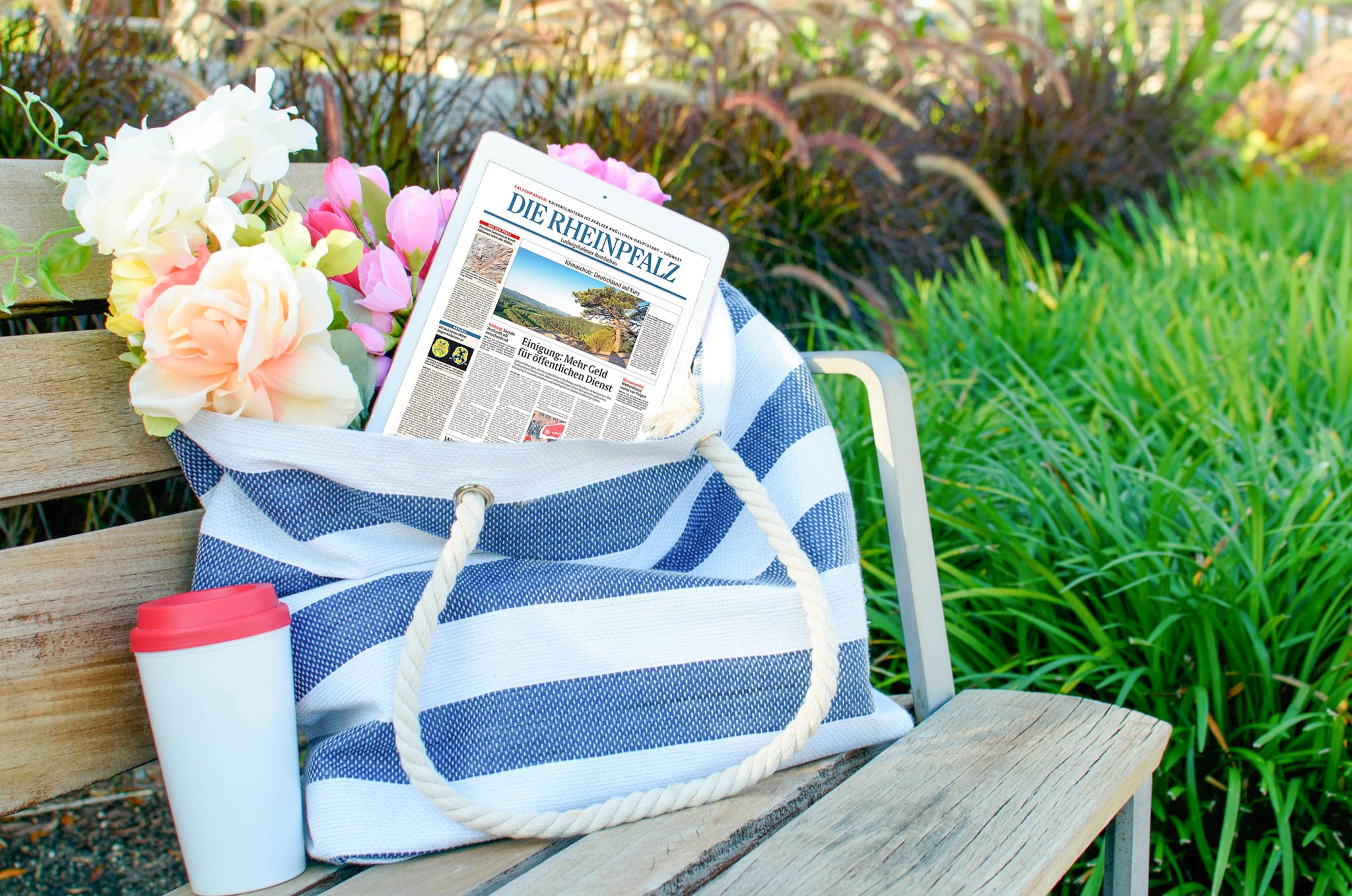 pexels-adrienne-andersen-1174503-2346986 - 09-05-2025 15-44-44-2 DIE RHEINPFALZ als Geschenk – Tablet mit der RHEINPFALZ in einer dekorativen Tasche mit Blumen. Daneben ein Thermobecher.