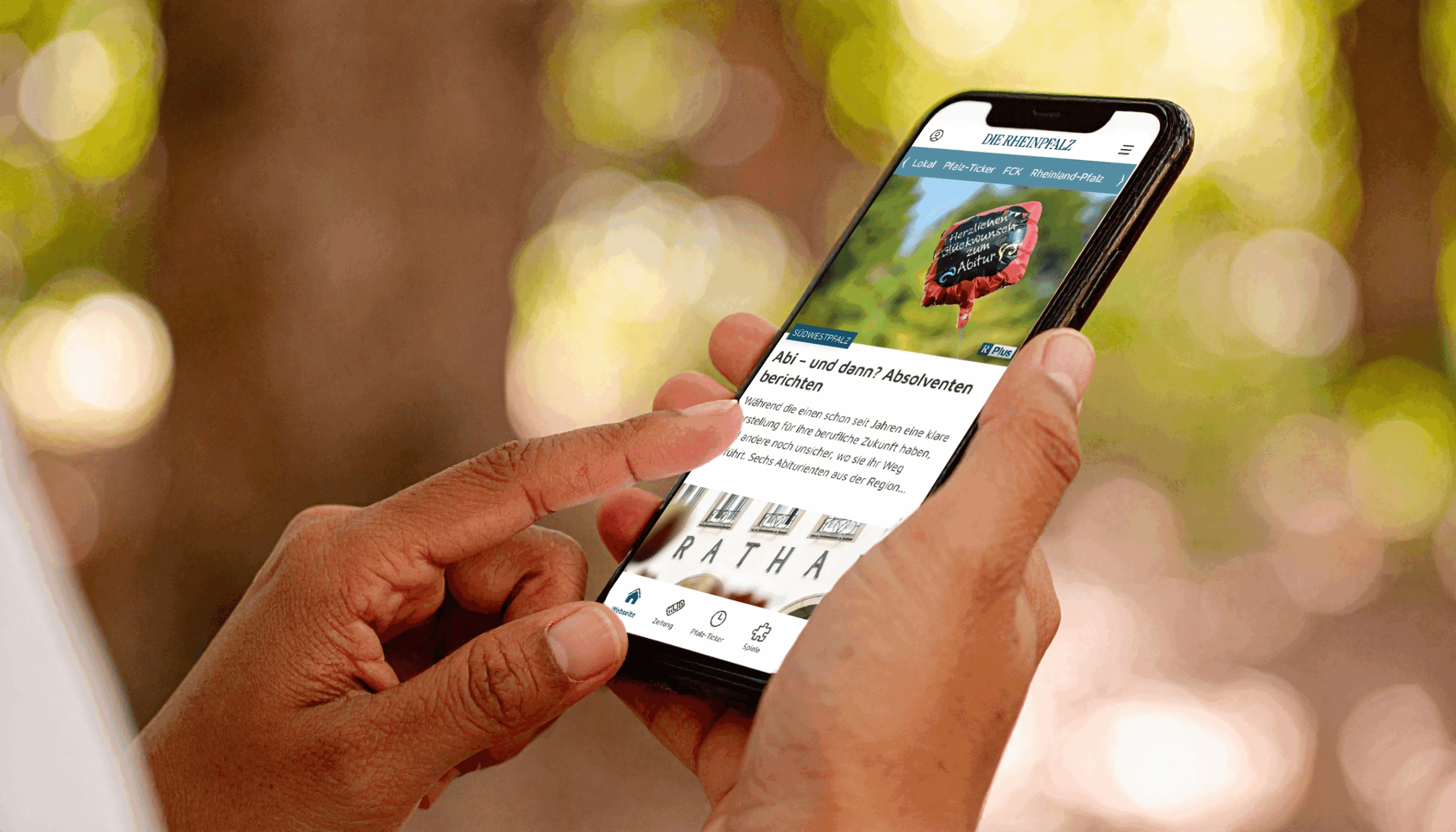 Person hält Smartphone mit der RHEINPFALZ-App – aktuelle Artikelübersicht geöffnet.