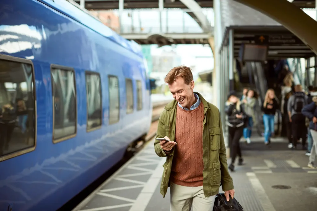 Ein Mann im besten Alter läuft den Bahnsteig entlang und liest dabei auf seinem Smartphone die RHEINPFALZ.