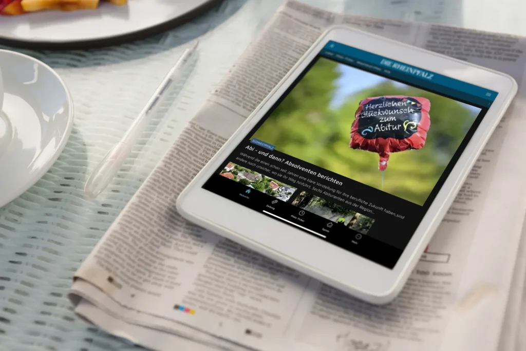 Ein Tablet liegt auf einer Print-Version der RHEINPFALZ. Es zeigt die Startseite der RHEINPFALZ App.
